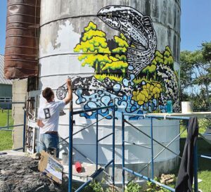 Artist paints natural landscape creeping up side of a silo