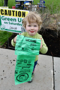 Three-year-old Liam Champman-Hale of MIddlebury is excited to put his Green Up bag and gloves to good use on Saturday as he collects his gear at College Park before heading out to pick up trash by the road. Independent Photo/Steve James